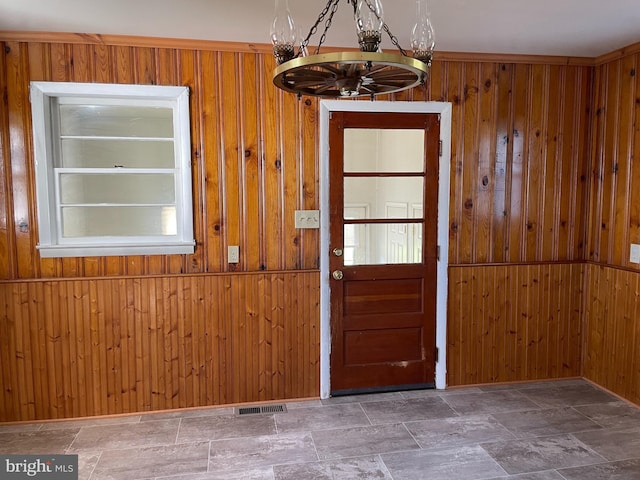 foyer with visible vents, stone finish floor, and wooden walls