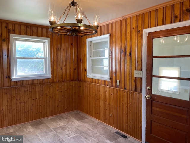 interior space with a notable chandelier, visible vents, and wooden walls