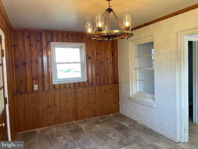 unfurnished dining area with a notable chandelier, wooden walls, and brick wall