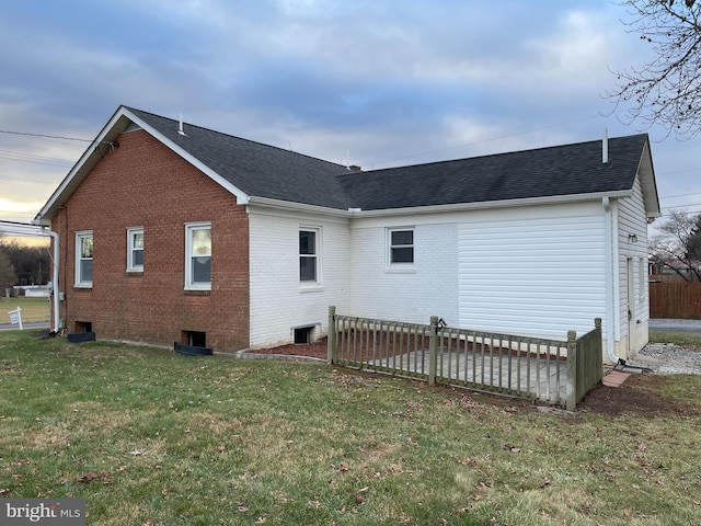 rear view of property with a lawn, brick siding, and roof with shingles