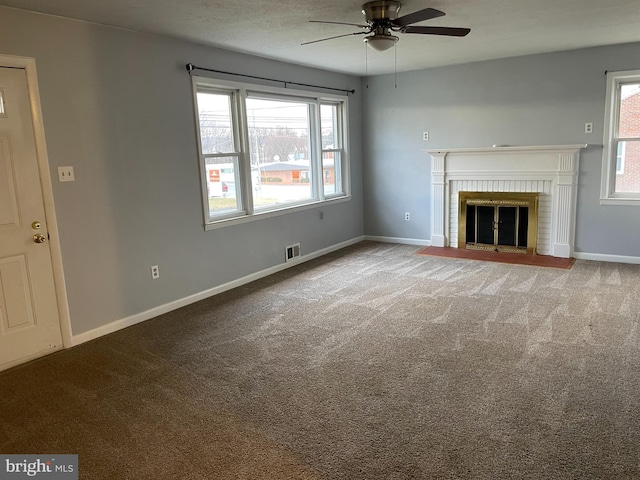 unfurnished living room with a brick fireplace, baseboards, visible vents, and carpet floors