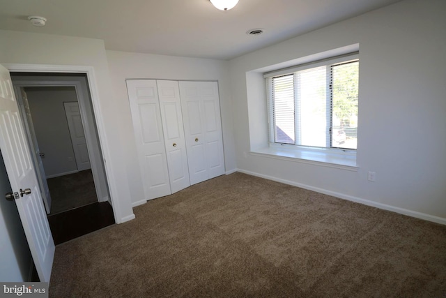 unfurnished bedroom featuring dark carpet and a closet