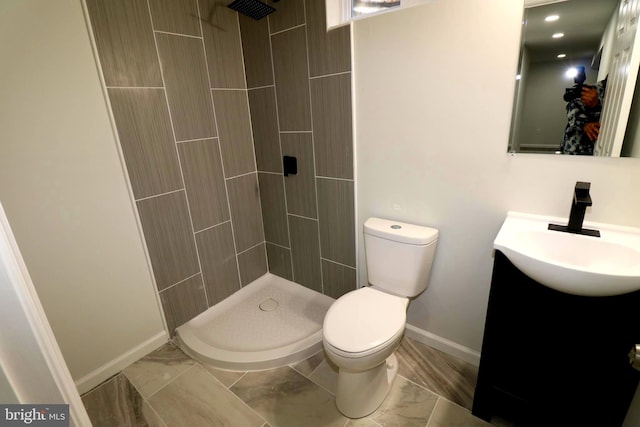 bathroom featuring tiled shower, vanity, and toilet