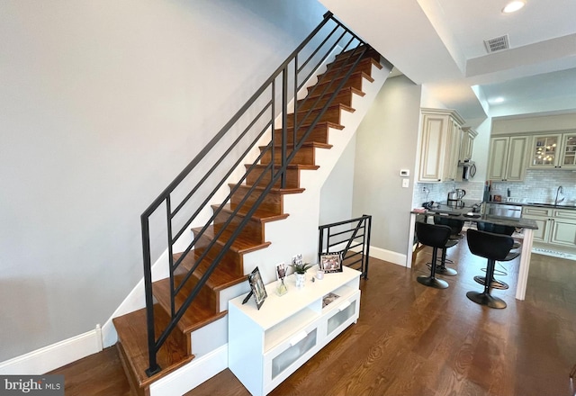 staircase with hardwood / wood-style floors and sink