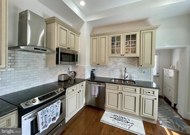 kitchen with cream cabinetry, dark hardwood / wood-style flooring, sink, appliances with stainless steel finishes, and wall chimney range hood