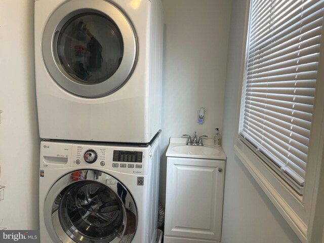 laundry area with cabinets, sink, and stacked washing maching and dryer