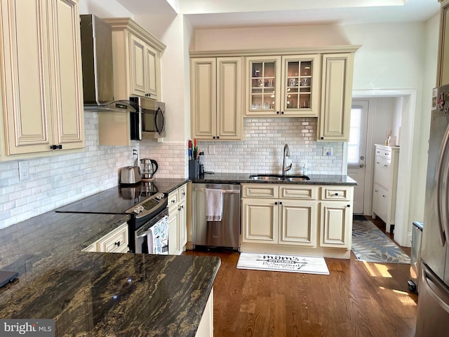 kitchen with dark hardwood / wood-style floors, wall chimney exhaust hood, appliances with stainless steel finishes, sink, and cream cabinetry