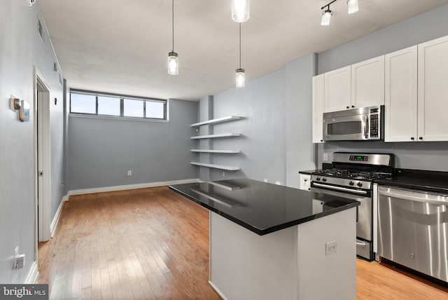 kitchen featuring a center island, white cabinets, light hardwood / wood-style flooring, appliances with stainless steel finishes, and decorative light fixtures