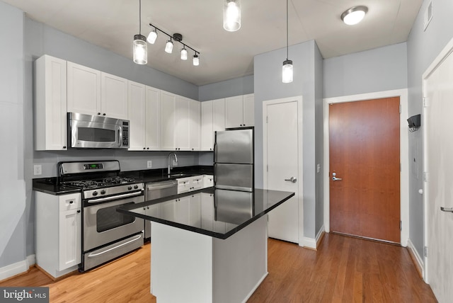 kitchen featuring pendant lighting, light hardwood / wood-style flooring, stainless steel appliances, and white cabinets