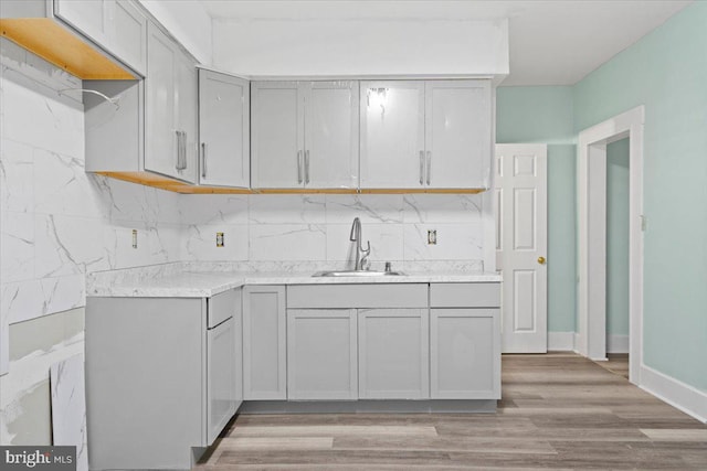 kitchen with sink, gray cabinetry, light wood-type flooring, and tasteful backsplash