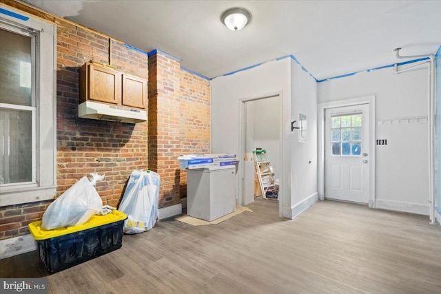 interior space with brick wall and light hardwood / wood-style floors