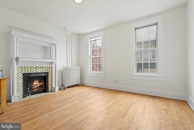 unfurnished living room featuring a fireplace, radiator heating unit, and light hardwood / wood-style floors