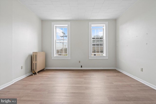 unfurnished room featuring light hardwood / wood-style flooring and radiator heating unit