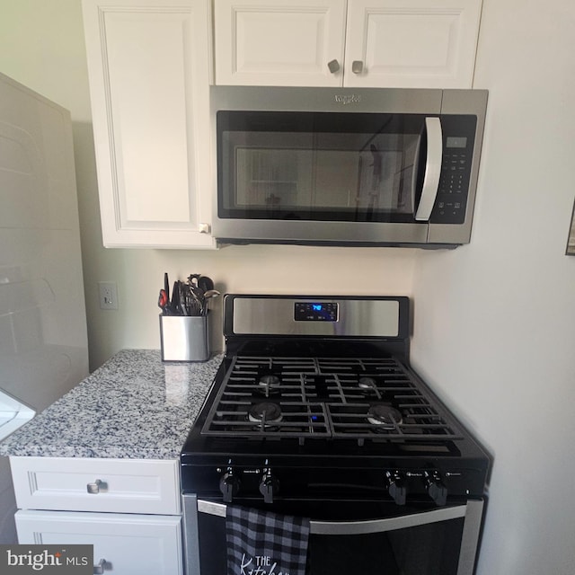 kitchen featuring white cabinets, appliances with stainless steel finishes, and light stone counters