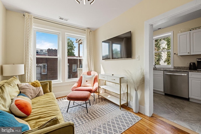 sitting room featuring visible vents, light wood-type flooring, and baseboards