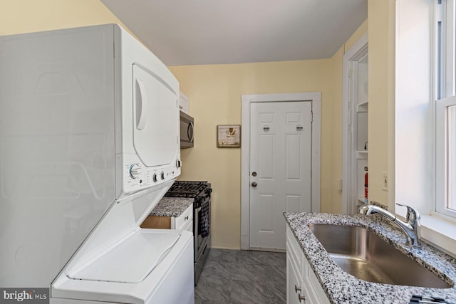 clothes washing area featuring stacked washer and clothes dryer and sink