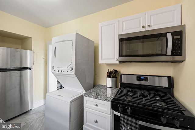 kitchen featuring white cabinets, stainless steel appliances, and stacked washer / dryer