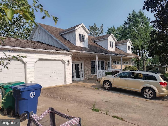 cape cod-style house featuring a garage and a porch