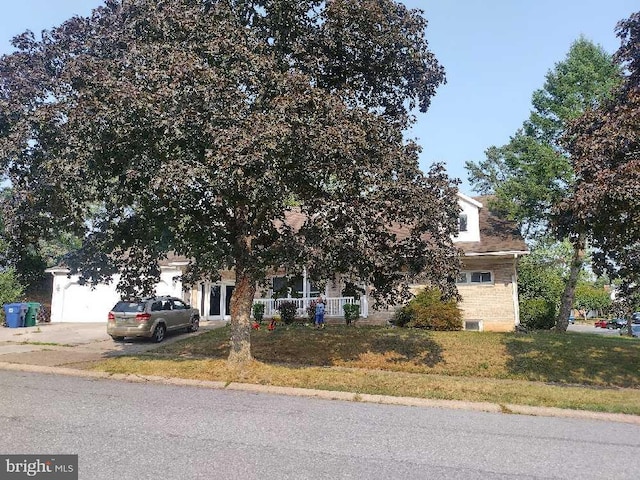 obstructed view of property featuring a front yard, an attached garage, and driveway