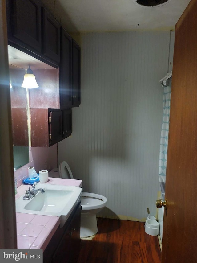 half bathroom featuring toilet, vanity, and wood finished floors