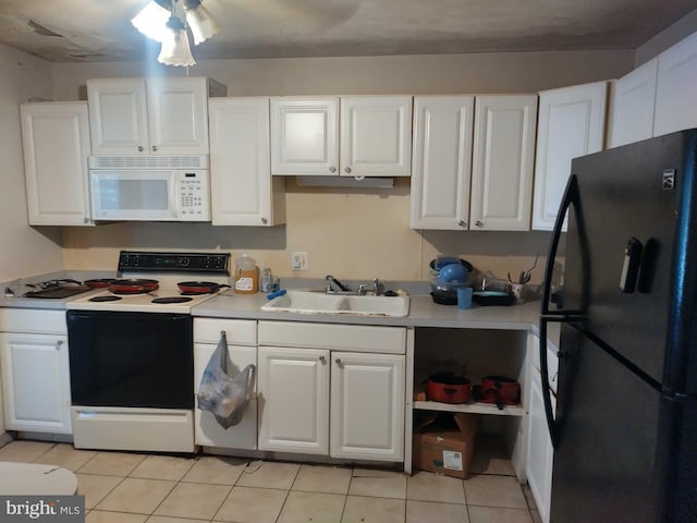 kitchen with electric stove, a sink, freestanding refrigerator, white cabinets, and white microwave