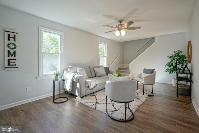 living room featuring dark wood-type flooring, a healthy amount of sunlight, and ceiling fan