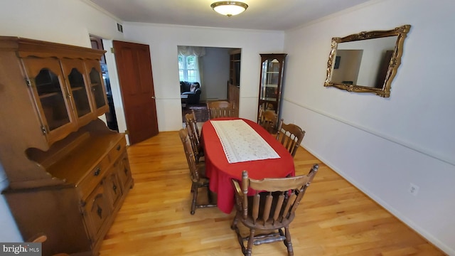 dining room with ornamental molding and light hardwood / wood-style floors