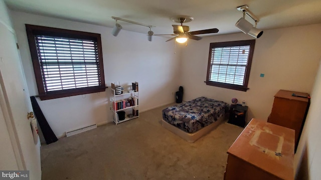 carpeted bedroom with a baseboard heating unit, multiple windows, and ceiling fan