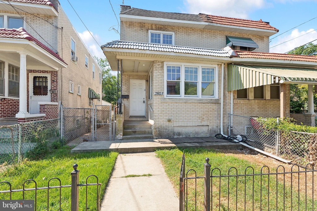 view of front of property featuring brick siding, fence private yard, a front lawn, and a gate