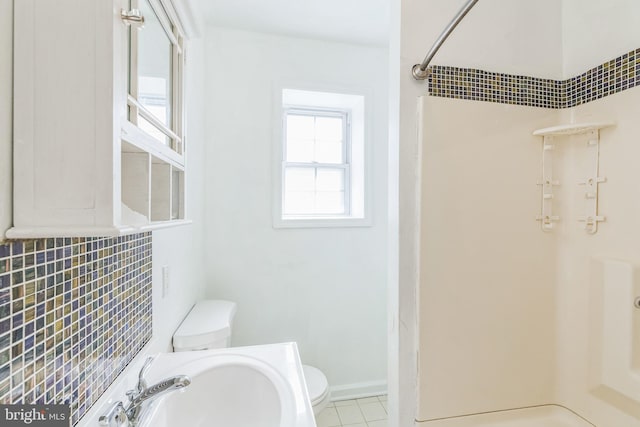 bathroom featuring a shower, toilet, sink, and tile patterned floors