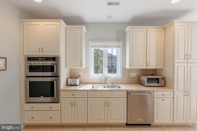 kitchen featuring sink, appliances with stainless steel finishes, backsplash, and light tile patterned flooring