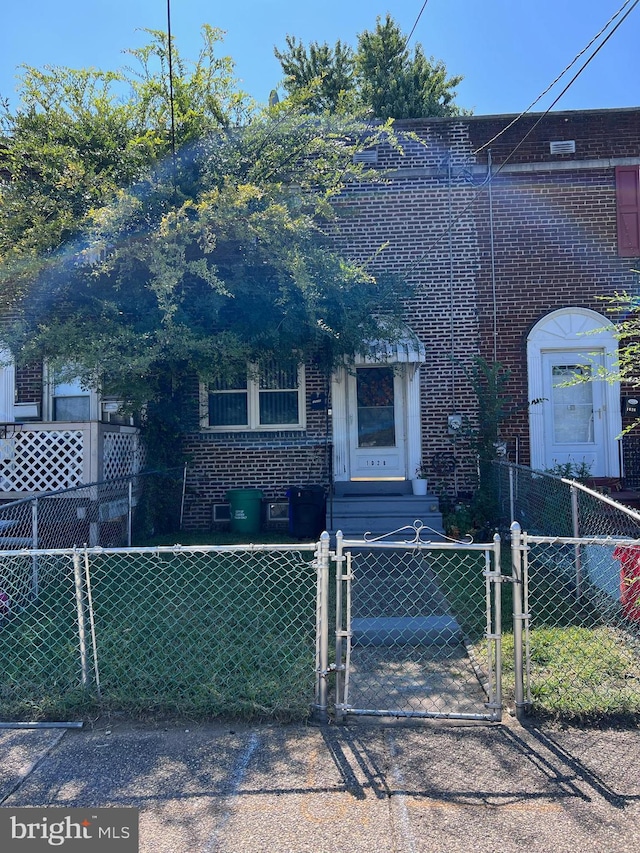 view of front of property with a fenced front yard, brick siding, and a gate