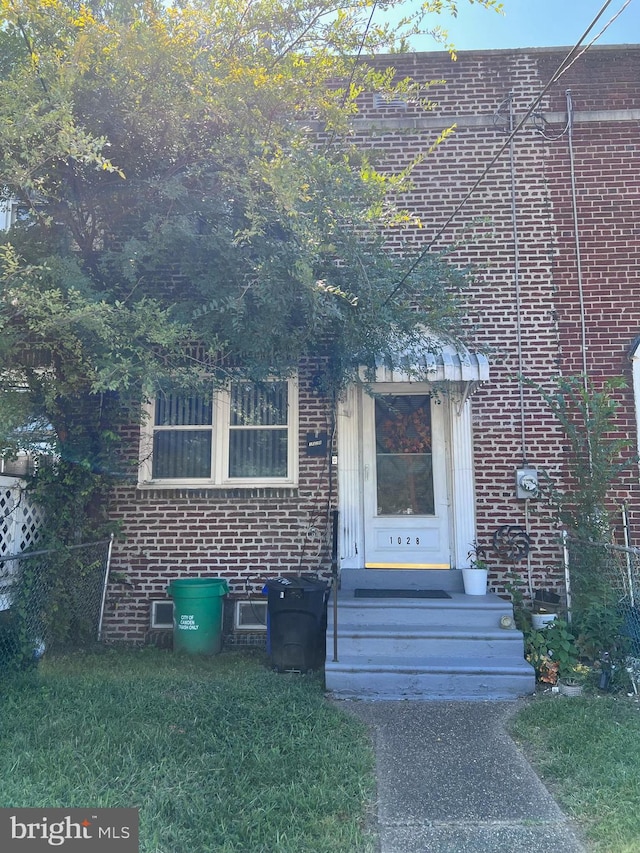 view of exterior entry featuring a lawn