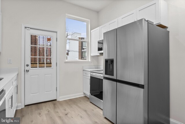 kitchen featuring stainless steel appliances, white cabinetry, and light hardwood / wood-style flooring