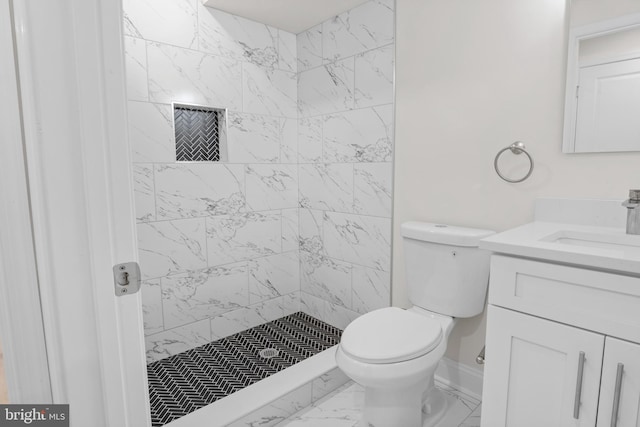 bathroom featuring vanity, toilet, and a tile shower