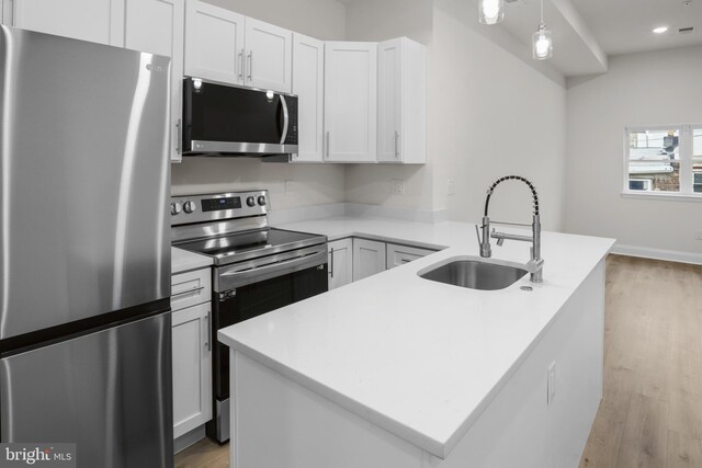 kitchen featuring white cabinets, appliances with stainless steel finishes, decorative light fixtures, and sink