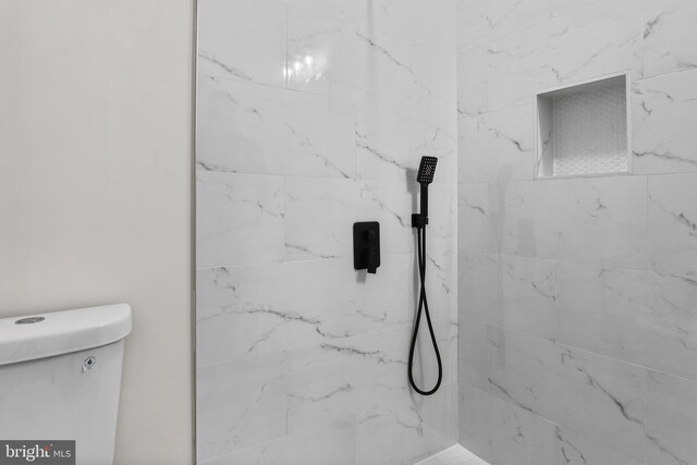 bathroom featuring tiled shower and toilet