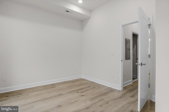 spare room featuring electric panel and light hardwood / wood-style flooring