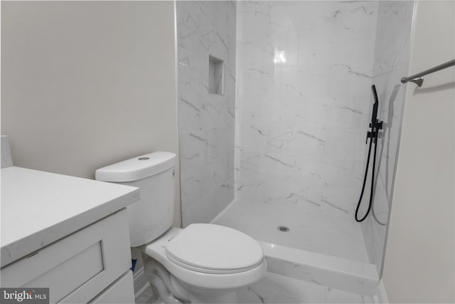 bathroom featuring toilet, a tile shower, and vanity