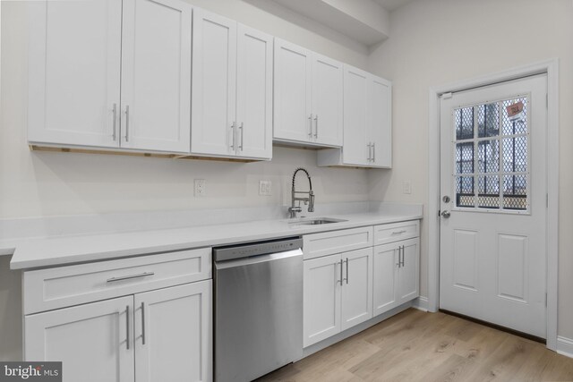 kitchen featuring stainless steel dishwasher, sink, white cabinetry, and light hardwood / wood-style floors