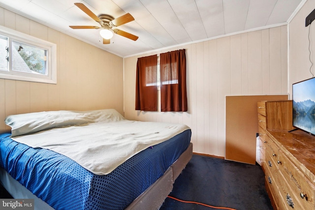 bedroom featuring wooden walls, dark colored carpet, multiple windows, and ceiling fan