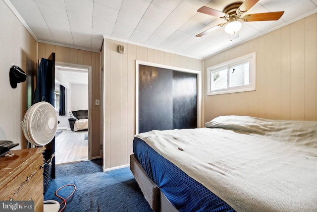 carpeted bedroom with ceiling fan, wooden walls, and crown molding