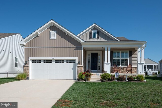 craftsman-style home with covered porch, a garage, and a front lawn