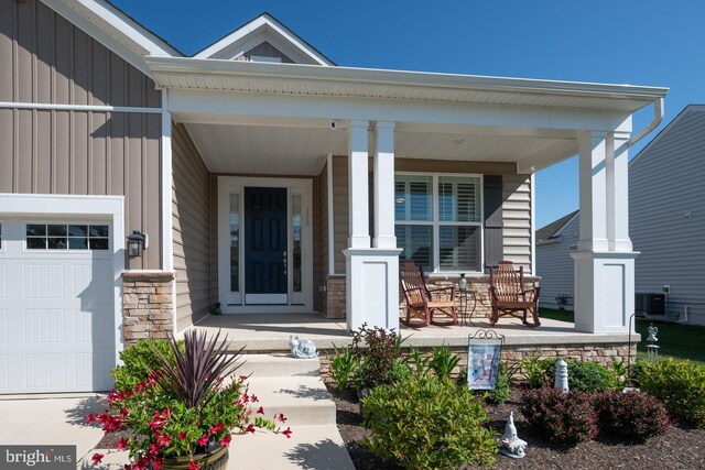 entrance to property featuring a porch, a garage, and central AC