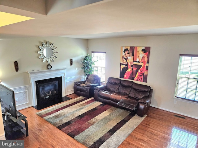 living room featuring lofted ceiling, hardwood / wood-style flooring, and a healthy amount of sunlight