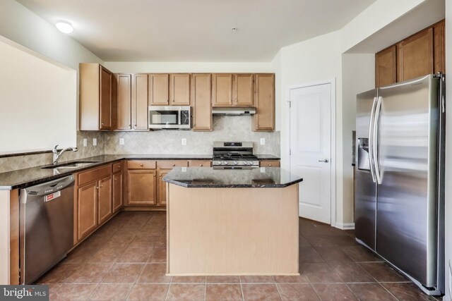 kitchen with stainless steel appliances, light tile patterned floors, backsplash, and dark stone counters