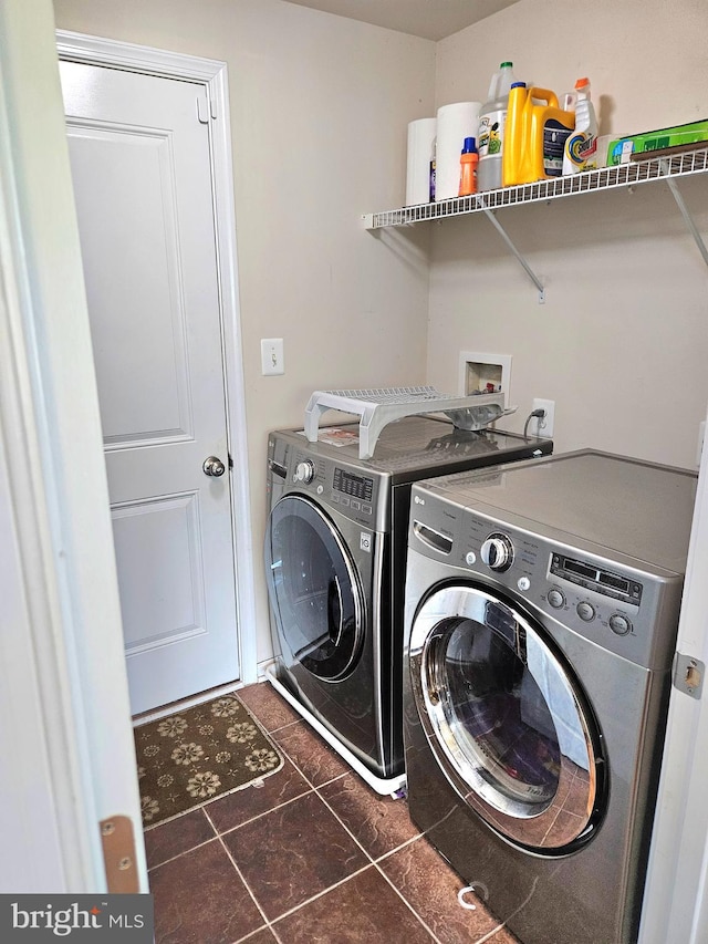 clothes washing area featuring dark tile patterned floors and washing machine and clothes dryer