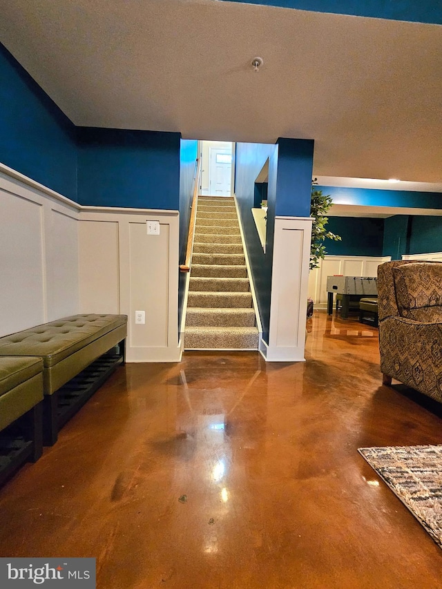 stairway with concrete floors and a textured ceiling