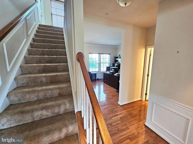 staircase featuring wood-type flooring and ornamental molding