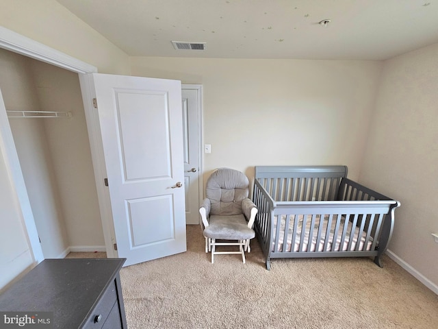 carpeted bedroom with a closet and a crib